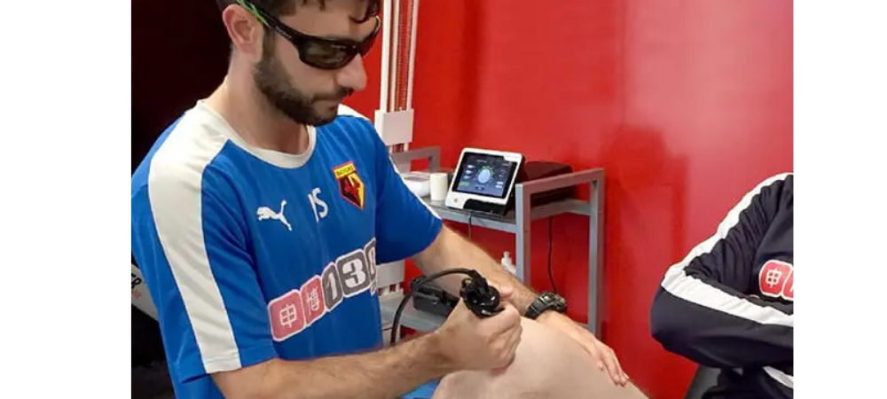 clinician applying laser to knee in athletic training room