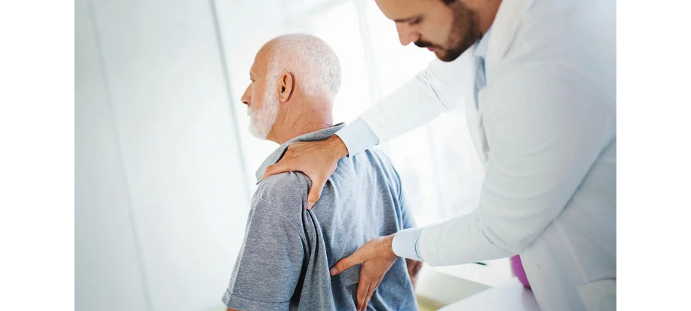 doctor assessing elder patient lower back