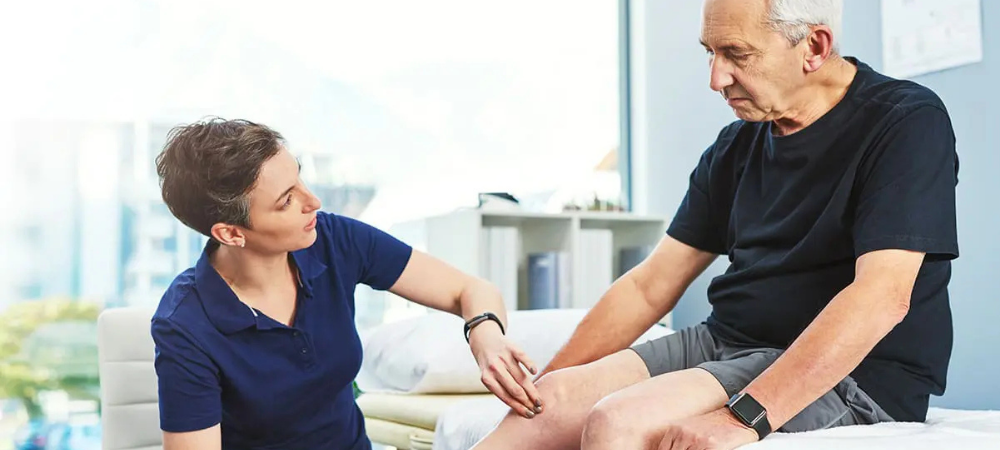 elderly man at physical therapist, doctor touching his knee