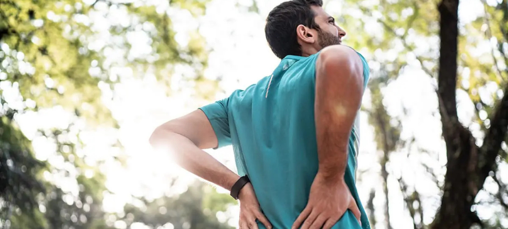 man looking upwards with his hands on his back