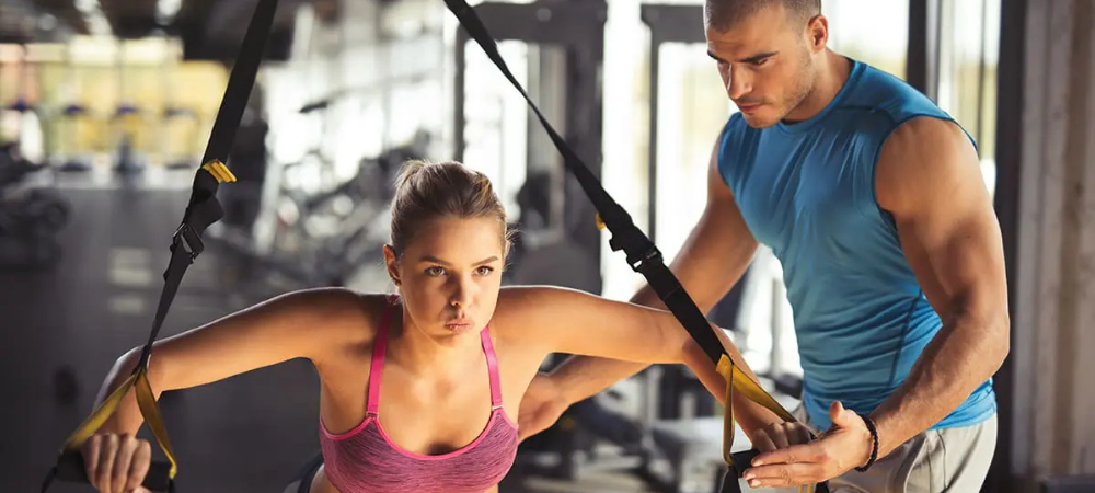 woman exercising with bands, coach helping her
