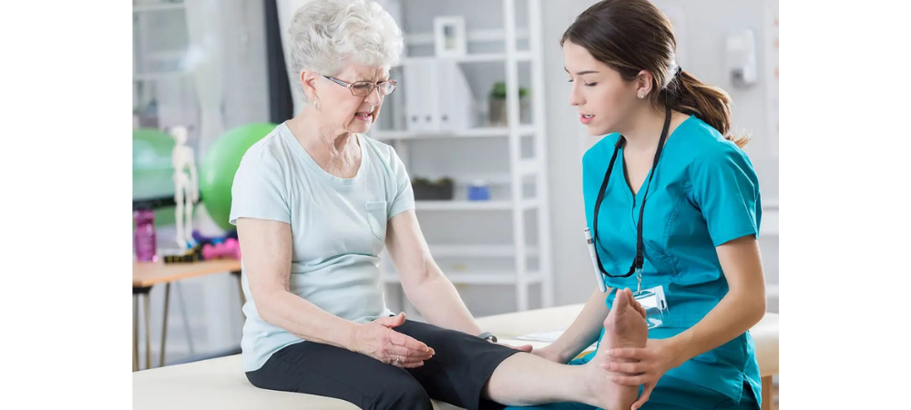 elderly woman sitting on treatment table with her leg up, signifying leg pain to doctor