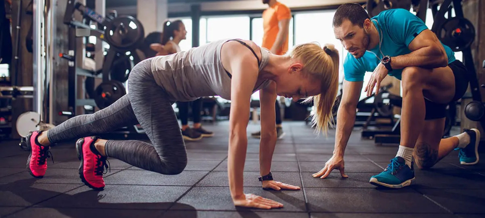 woman exercising at gym with trainer
