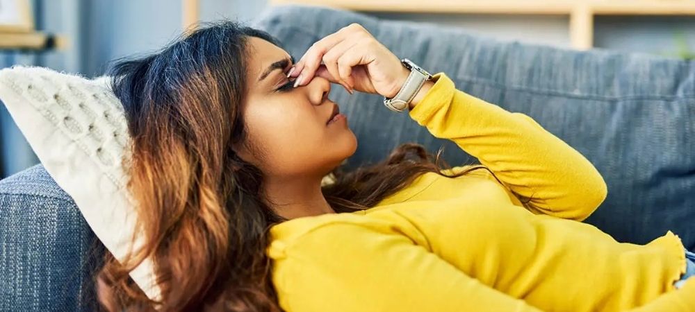 woman with headache laying on couch